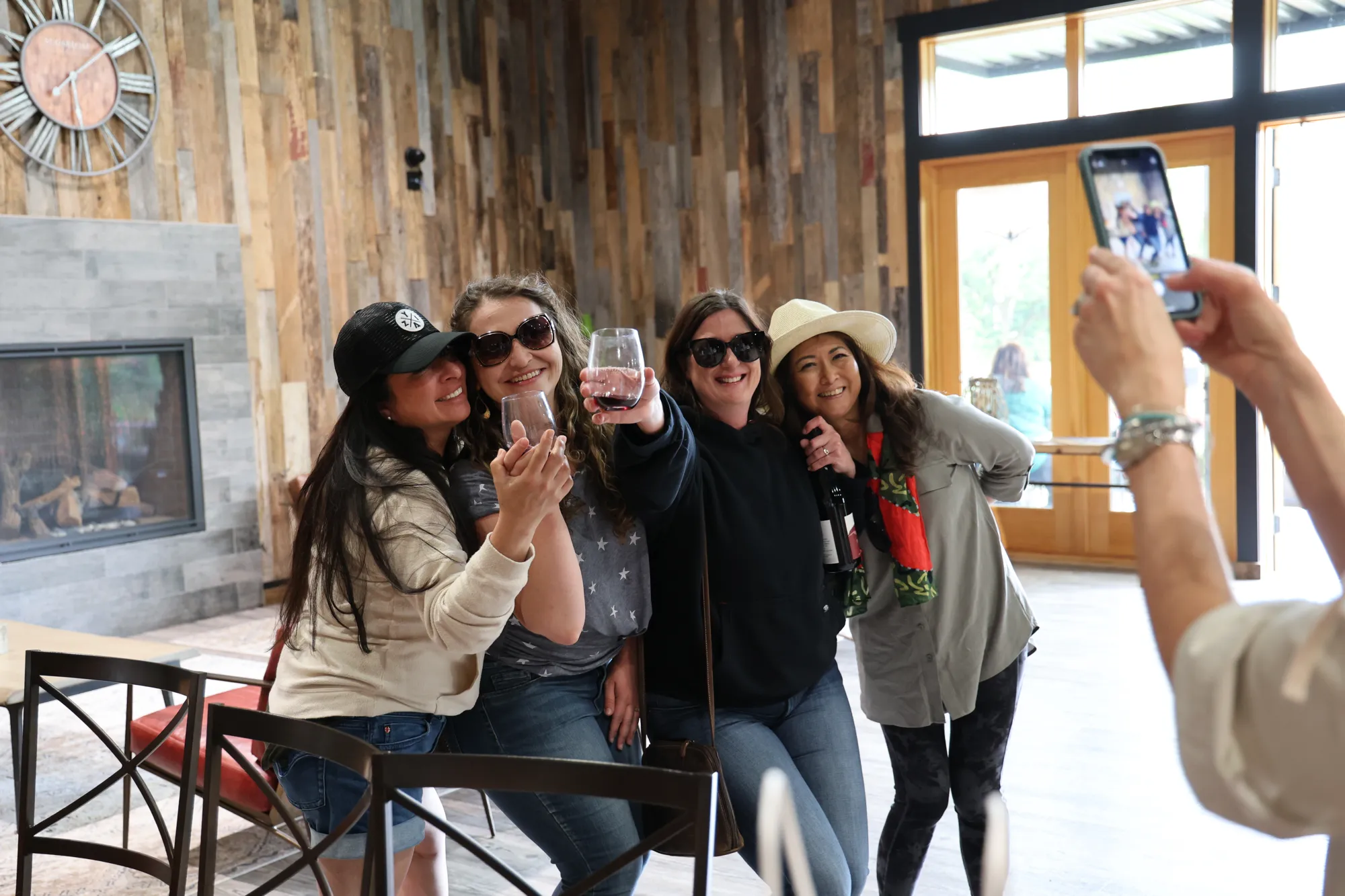 Woman taking iphone photo of four women wine tasting inside tasting room and lounge, indoor event venue, Santa Rosa, CA, Sugarloaf Wine Co.